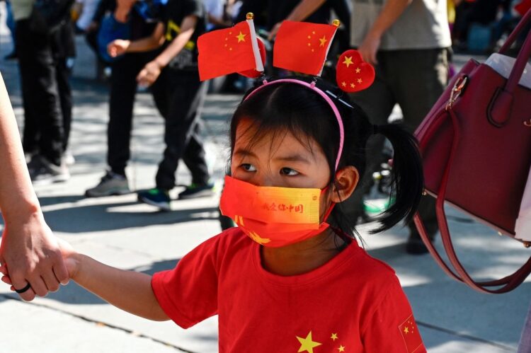 2021年10月1日、中華人民共和国72周年を祝う行列に参加する女の子。マスクには「私は中国を愛します」と書かれている（AFP＝時事）