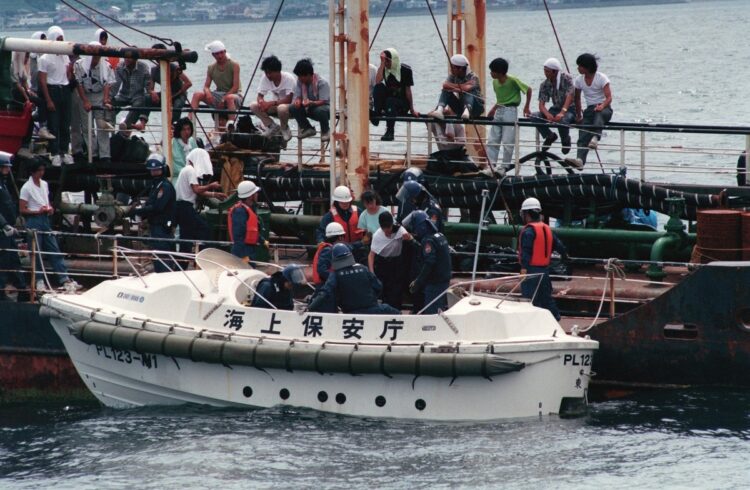 1994年7月、小型ボートを使って巡視船へ移送される集団密入国の中国人たち。蛇頭は主に中国福建省を拠点とする密入国を斡旋するブローカー犯罪組織だった（時事通信フォト）