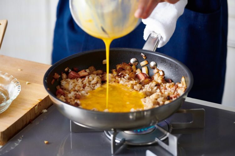 フライパンの端に具材を寄せ強火にし、空いたところに溶いた卵を入れてご飯と混ぜながら炒める