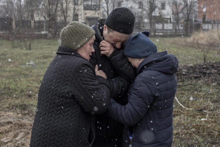 集団埋葬地の前で行方不明の親族を思い涙を流すウクライナ人の家族（共同通信社）