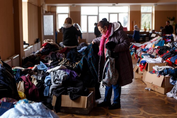 ウクライナ西部の町で支援物資の衣類を手にする女性（共同通信社）
