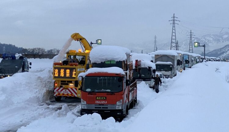2020年12月、大雪により関越自動車道上り線塩沢石打インター手前で立ち往生した車両の列。左は除雪車（時事通信フォト）