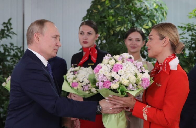 国際女性デーに乗り合わせた乗務員に花をプレゼントするプーチン大統領（SPUTNIK/時事通信フォト）