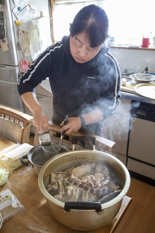 湯気が立つできたての鍋を前にする河崎氏