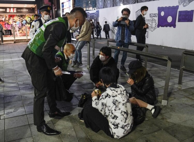 歌舞伎町の東宝ビル横、通称トー横に集まる若者には精神的に不安定な人が少なくない。2021年4月、コロナ感染対策のため帰宅を呼びかける都庁職員（イメージ、EPA＝時事）
