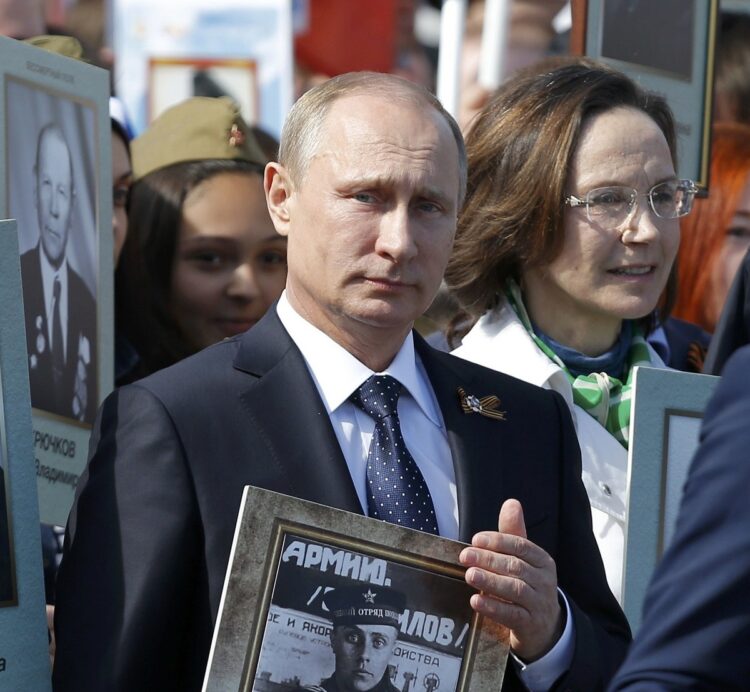父の遺影を掲げて行進するプーチン氏（写真／ロイター=共同）