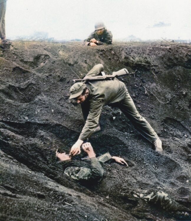 硫黄島では、砲弾孔に2日間埋まったままの日本兵へアメリカ兵が煙草を差し出した。写真＝庭田杏珠 × 渡邉英徳『AIとカラー化した写真でよみがえる戦前・戦争』（光文社 2020年）より