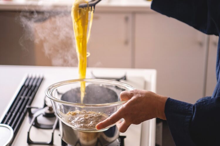 茹でた麺をボウルに入れ、具材と共にまぜる