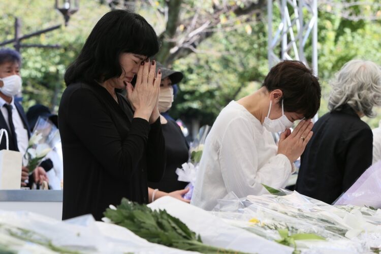 場外に設置された献花台の前で追悼する人々（写真／JMPA）