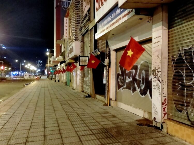 国慶節（9月2日）を間近に控え、ベトナム国旗が翻るホーチミン市内。コロナ以前はあまり見られなかった落書きが店舗のシャッターに目立つ（ホーチミン市、2022年8月下旬）
