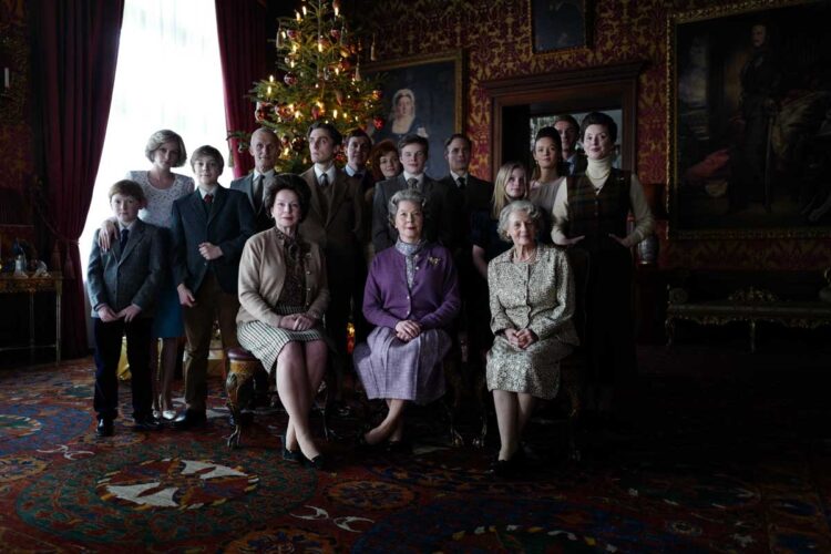 クリスマスの集合写真のシーン。前列中央に座るのはエリザベス女王で、王室伝統のロイヤルパープルの衣装を身に着けている。2列目左からヘンリー王子、ウィリアム王子、少し離れて夫婦関係が破綻していたチャールズ皇太子。ダイアナは両王子に寄り添って立っている（C）Pablo Larrain