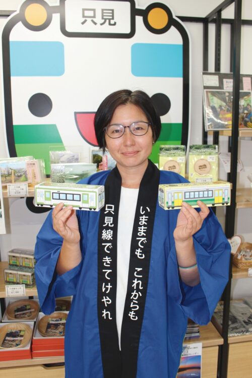 酒井さんは、土日祝日に交代制で列車に乗ってガイドや沿線地域の特産品の車内販売も行なう。手にするのは只見町産発芽玄米を使った「ポンせん」