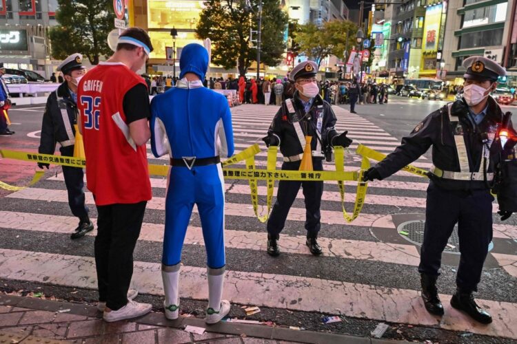 渋谷ハロウィンのためにコスプレしてやってきた人たちと警備の警察官たち（AFP＝時事）