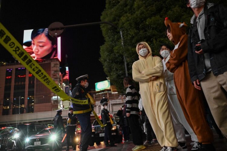 渋谷駅前のスクランブル交差点を渡るのを待つハロウィンのためにコスプレした人たち（AFP＝時事）