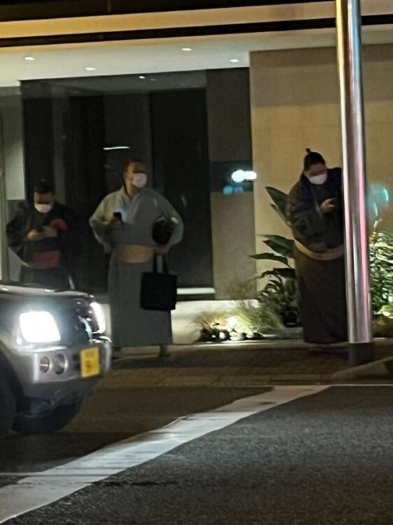 タクシーを待ちながら、街頭の柱にテッポーのような仕草を見せる逸ノ城(右)