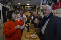 神棚が見下ろす細長い空間で「年齢は秘密よ」と笑う優しい店主（写真左）と乾杯！