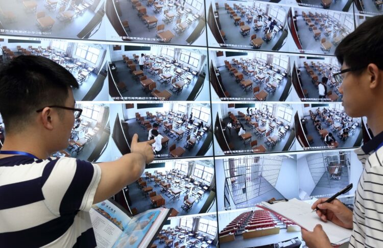 中国の国立大学入試の前に、教室で監視カメラのライブ映像を映し出す大画面をチェックする中国の試験官。この入試では顔認識、指紋認証、金属探知機などの複数のチェックポイントを通過した後、ようやく学生は入学試験を受ける無線シールドが張り巡らされた試験会場へ入れる（Imaginechina/時事通信フォト）