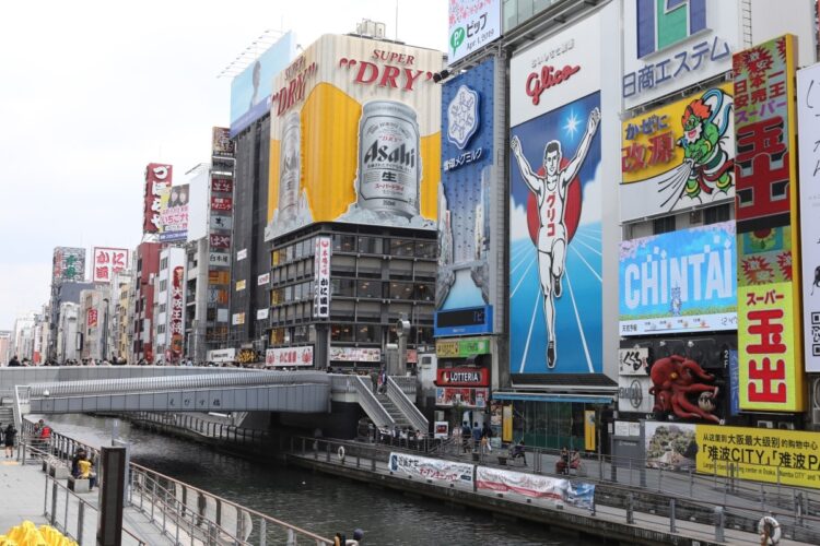 道頓堀川に架かる戎橋と、グリコなどの巨大な看板。戎橋の下に若者たちが自然発生的に集まるようになり、グリコサインの下、略して「グリ下」と呼ばれるようになった（時事通信フォト）