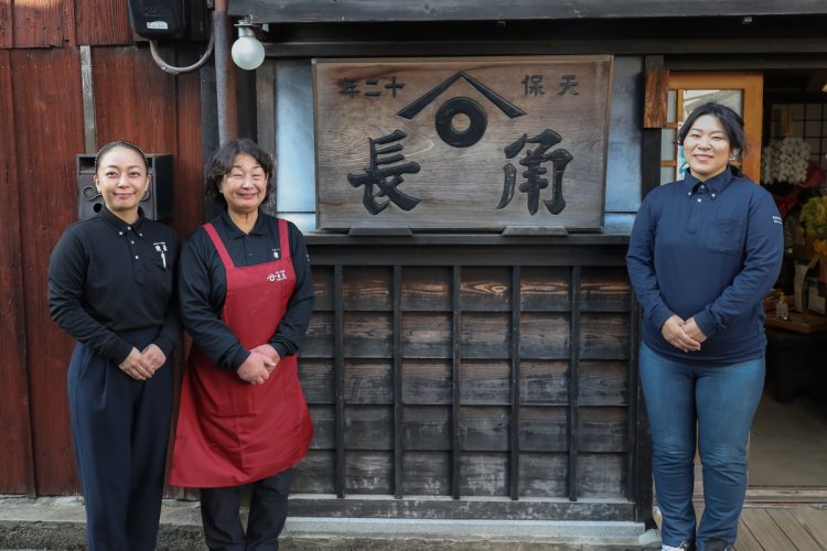 「角長」の看板を囲んで、左から長女・智子さん、左起子さん、長男の妻・千秋さん