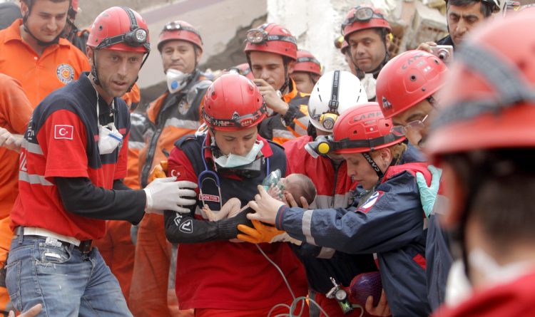 
トルコ東部のエルジシュで、倒壊した建物から救出され、救助隊員に抱えられながら病院へと運ばれる生後2か月の赤ちゃん（時事通信フォト）