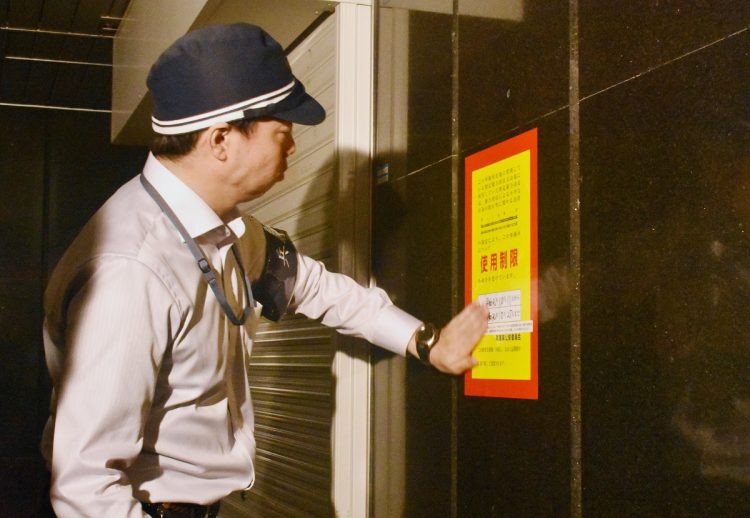 暴力団事務所に使用制限仮命令の紙を張る兵庫県警の警察官（時事通信フォト）