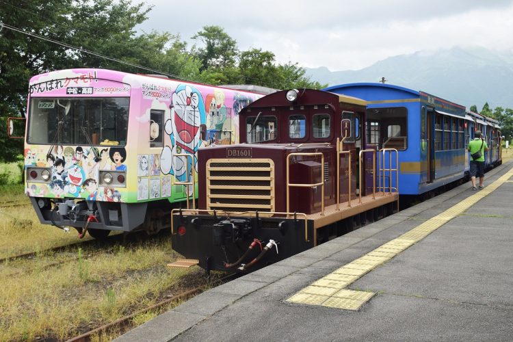 南阿蘇鉄道のトロッコ列車「ゆうすげ号」（右）と、アニメの人気キャラクターなどが描かれたラッピングトレイン。熊本県高森町の高森駅（時事通信フォト）
