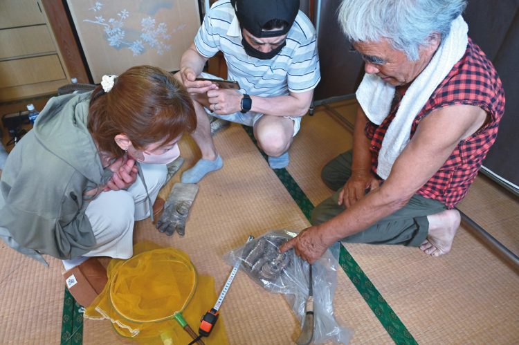 屋根裏から駆除したキイロスズメバチの巣を確認する依頼者家族。「まさか家の中にスズメバチの巣があるなんて。驚きました。これで安心です」（Aさん夫妻）