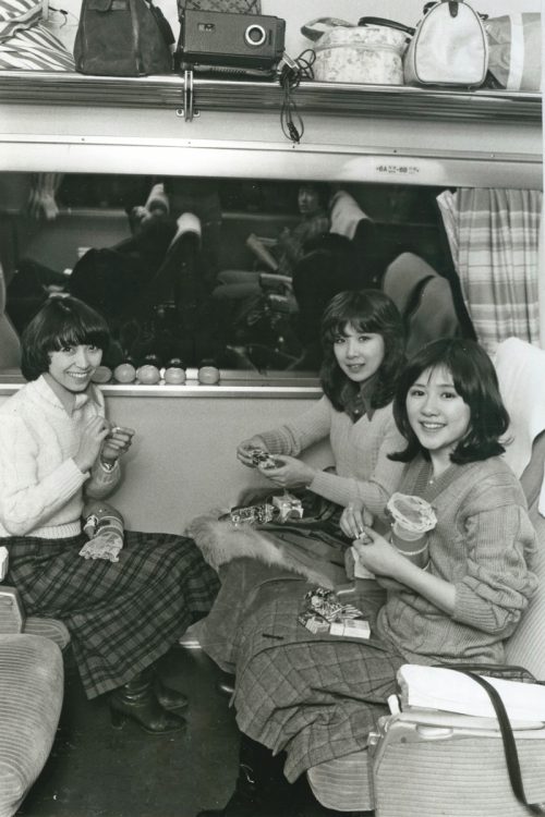 1974年、移動中の電車内で、クリスマスブーツからお菓子を取り出している仲睦まじい3人（C）女性セブン