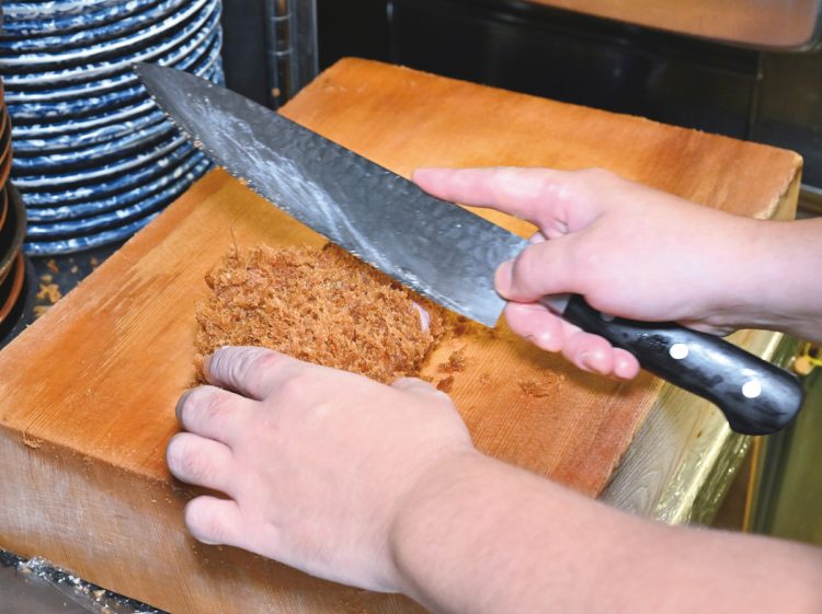 揚げ上がったロースかつを余熱で仕上げる。切るたびにザクザクと響く音が心地よい。衣に使用するのは特注の生パン粉