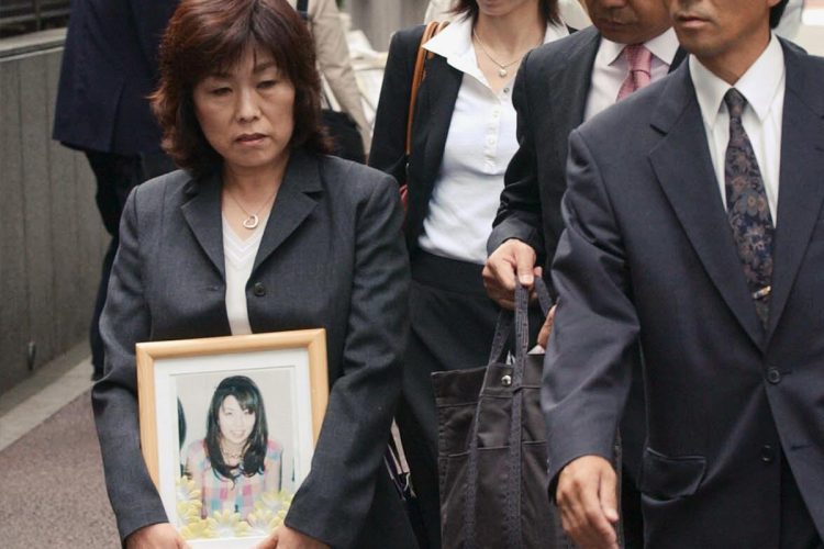 国家賠償訴訟第１回口頭弁論で、猪野詩織さんの遺影を持ち東京高裁に入る母・京子さん（時事通信フォト）