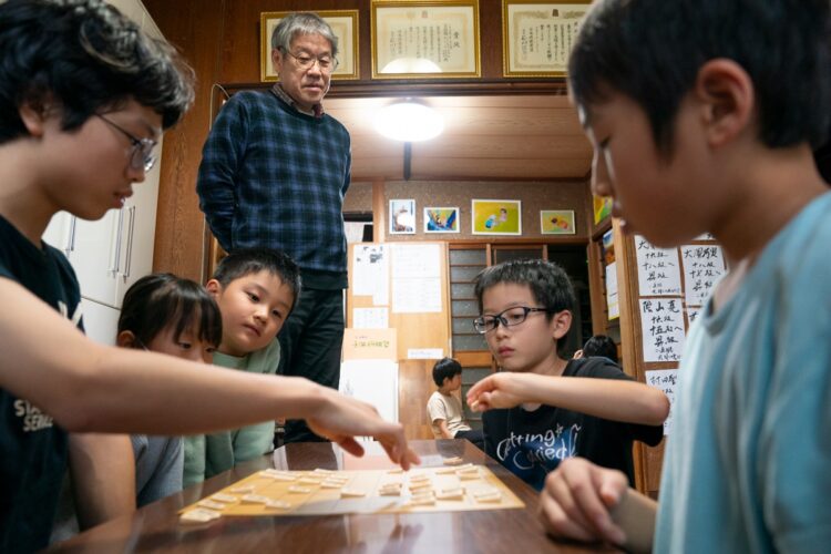 「ふみもと子供将棋教室」の生徒数は現在約30人。幼稚園から中学生までを対象にしている。文本さん（写真中央）は将棋教室では、集中力と思考力が鍛えられると言う。「聡太は学校の成績もすごいよかった。こんな小さな教室からでも、東大に入った子が３人いるんですよ」