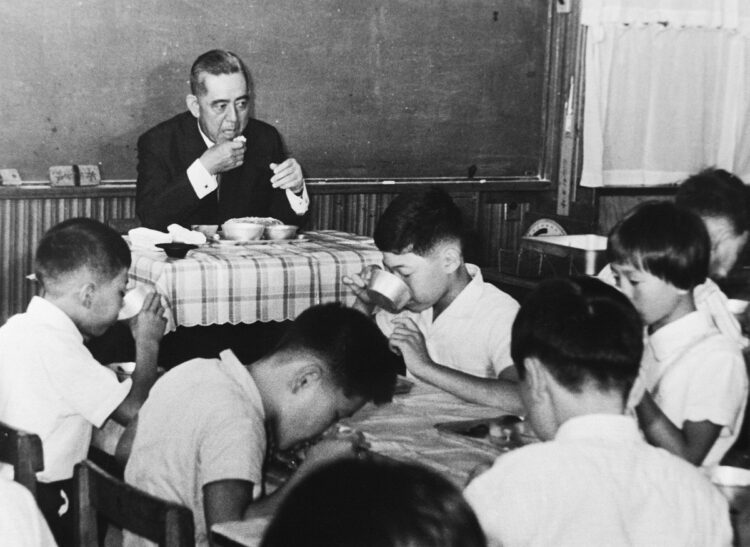 1966年、教室で小学6年生と一緒に給食を食べる佐藤栄作首相。佐藤首相はへき地にある学校の給食施策改善に注力、全国で給食の実施率が上昇した（時事通信フォト）
