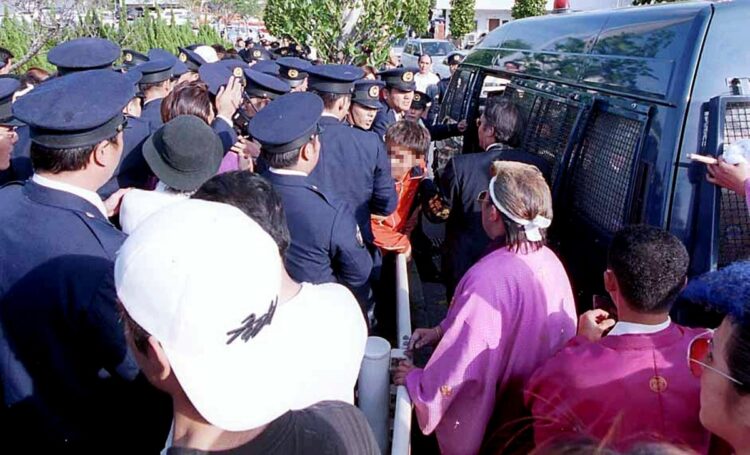 2002年、成人式会場前でワゴン車で車止めに突っ込むなどした新成人や少年を道交法違反の現行犯で逮捕、連行する沖縄県警の警察官（時事通信フォト）