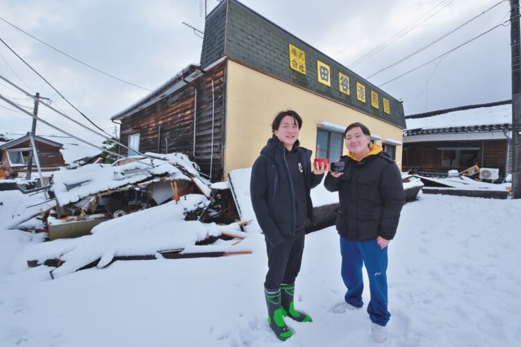 1階が押し潰された工場の前で、見つけ出した輪島塗の器を手に復活を誓う田谷昂大さん（左）といとこの田谷竜一さん