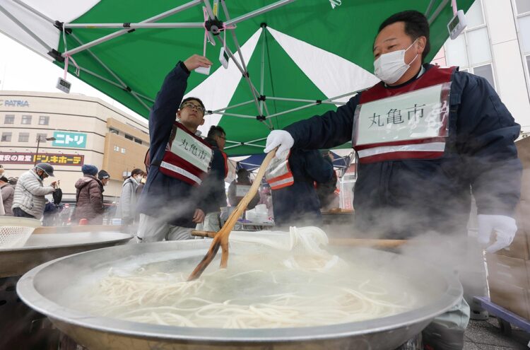 親善都市の香川県丸亀市は、七尾市で名物讃岐うどんの炊き出し。厳しい冷え込みの中、集まった被災者たちは笑顔で舌鼓を打った（時事通信フォト）