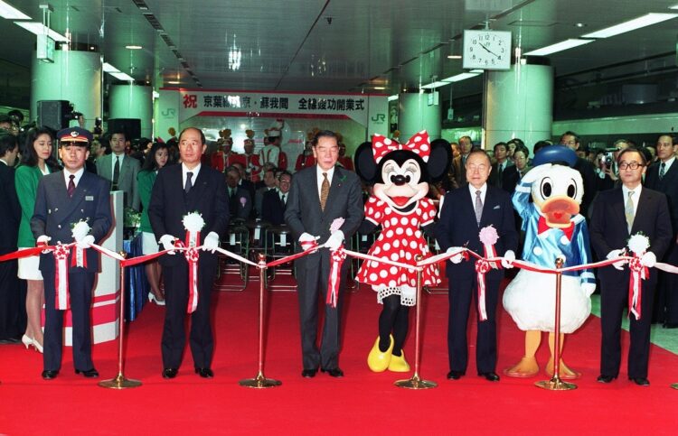 京葉線東京-蘇我間全線竣工開業式は1990年3月10日。沿線にある東京ディズニーランドのキャラクターとともにテープカットする(左から)木下秀彰東京駅長、住田正二JR東日本社長、大野明運輸相、鈴木俊一東京都知事ら(時事通信フォト)