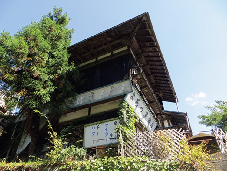 城のような石垣の上にある、年季の入った土産店には「よろづ屋商店」の文字が