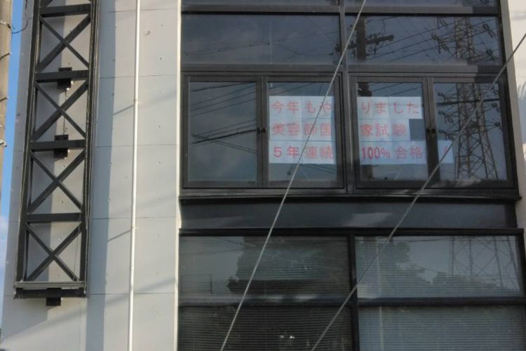 美容専門学校の窓には「美容師国家試験5年連続100%合格」と貼られてた（現地にて撮影）