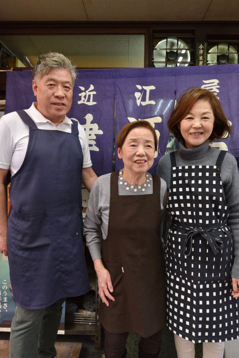 店主の今津春江さん（中央）を囲み、娘の光代さんと夫の三晃さん