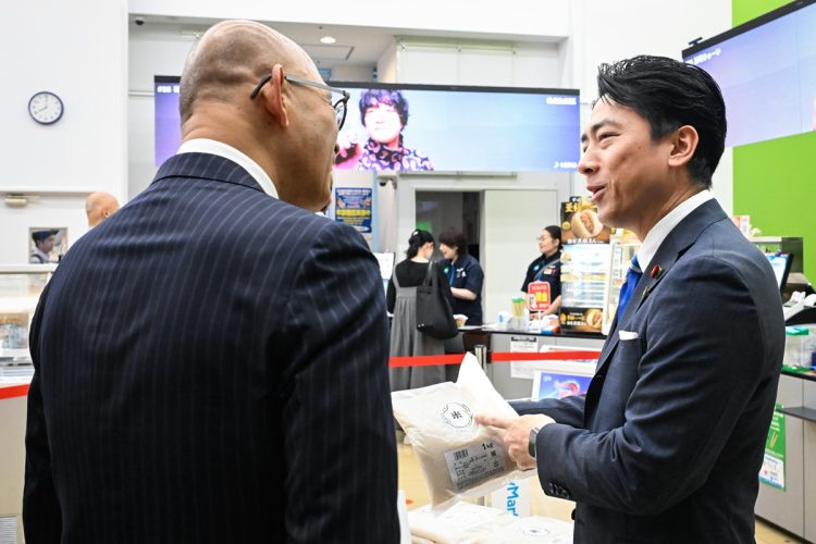 政府備蓄米を随意契約で調達した大手コンビニ「ファミリーマート」の販売状況を視察する小泉進次郎農林水産相(右)。6月5日(時事通信フォト)