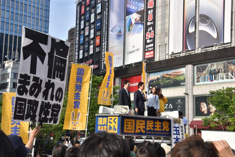 参院選の候補予定者と東京・千代田区の秋葉原駅前で街頭演説する玉木代表。同時点で山尾氏を公認することが伝えられていたため、"不倫まみれの国政政党"といった批判的なプラカードを持つ抗議者もいた。(2025年5月撮影:小川裕夫)