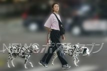ピンク色のシンプルなTシャツに黒のパンツ、足元はスニーカーというラフな格好