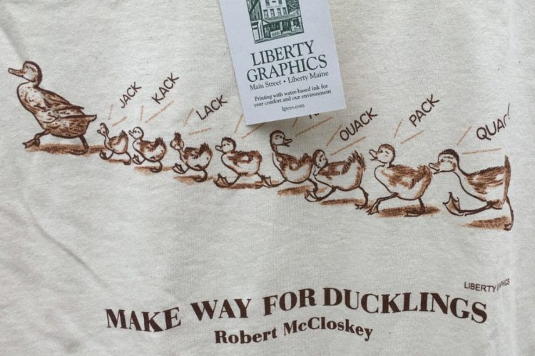 Tシャツには1列になって町の中を歩くカモの親子がプリントされている(アメリカのオンラインマーケットプレイス・オークションサイトより)