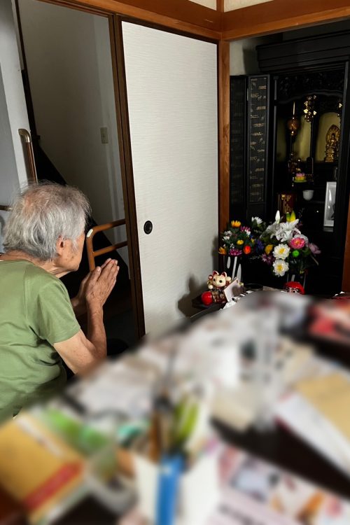 仏壇の前で手を合わせる世志氏