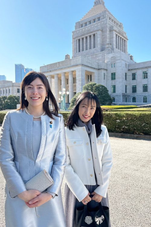秘書とのツーショット。2024年の国会の開会式でも銀色のスーツを着用(Xより)
