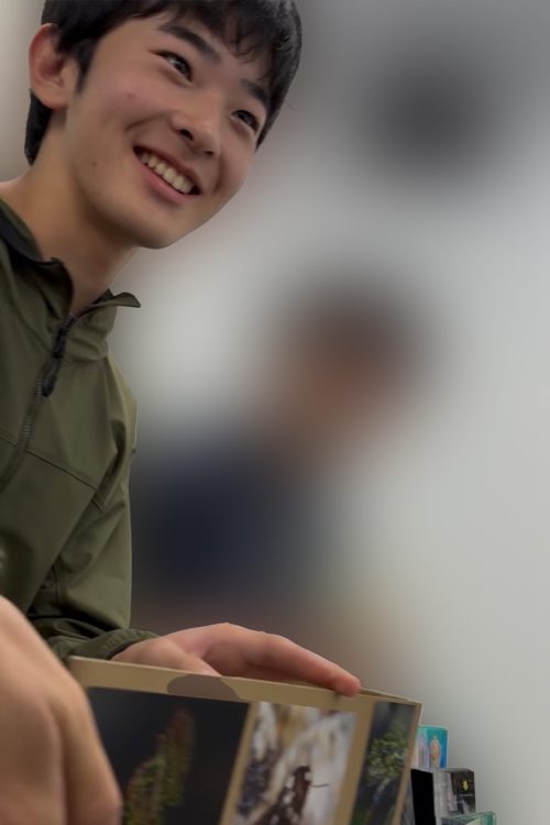 ポストカードの写真について説明している悠仁さま（学生提供）