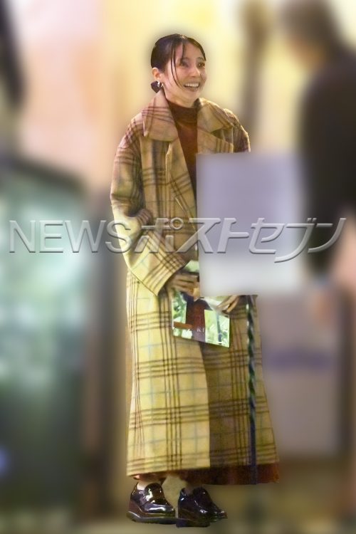 大柄チェックのコートを着用