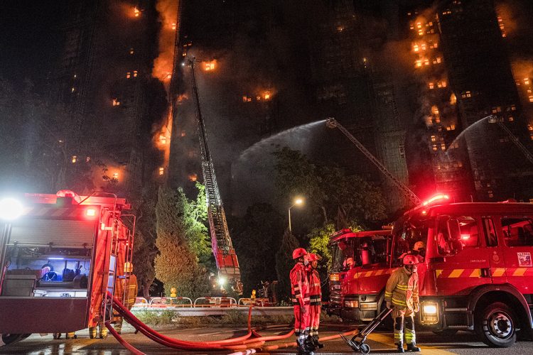 香港北部・大埔で起きた高層住宅火災で消火活動に当たる消防隊員ら(時事通信フォト)