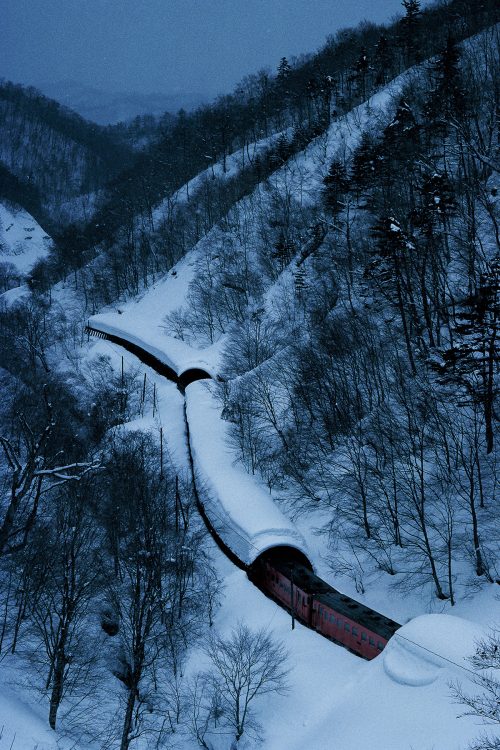 春先に雪崩が多く、かまぼこ形の雪除けが続く江差線吉堀〜神明間を走るキハ22 +キハ40（車両形式）。1985年（C）広田尚敬