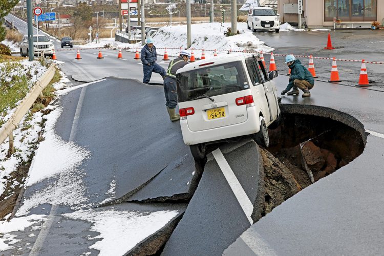 今回の地震で道路の陥没に巻き込まれた軽自動車（青森県東北町。写真／共同通信社）